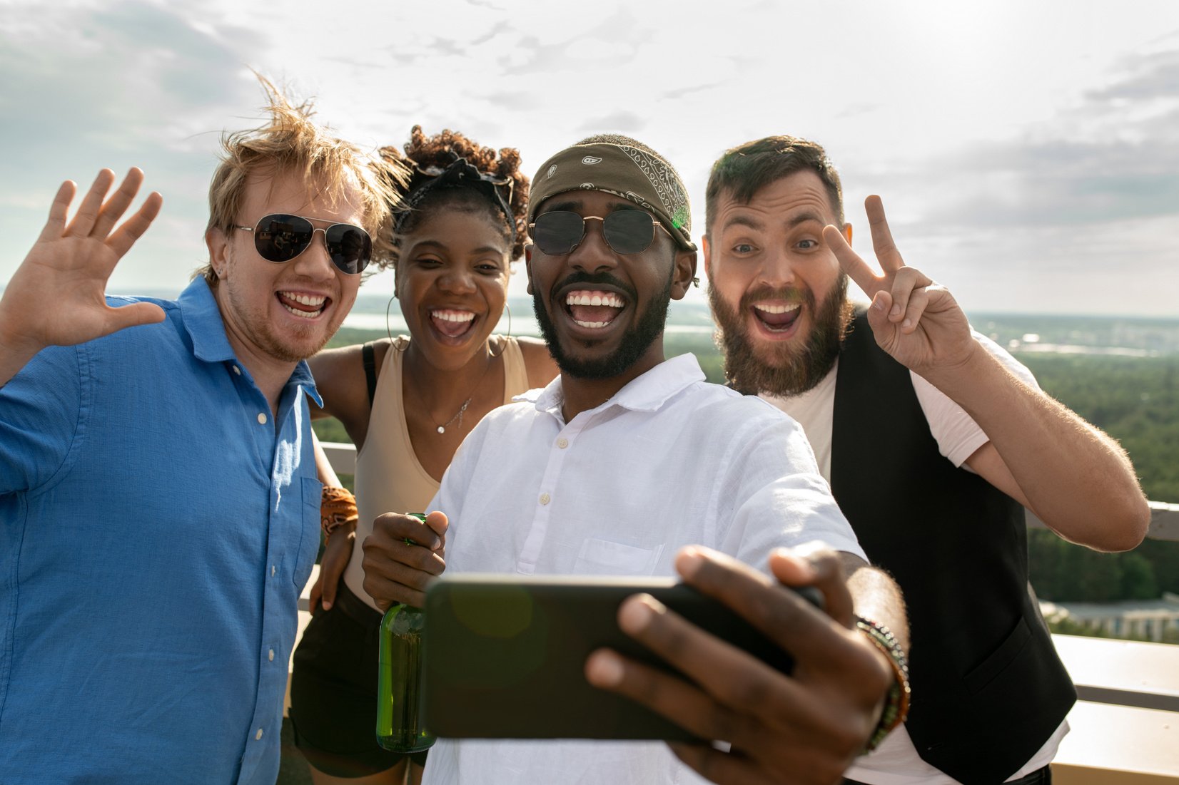 Cheerful intercultural friends making selfie outdoors